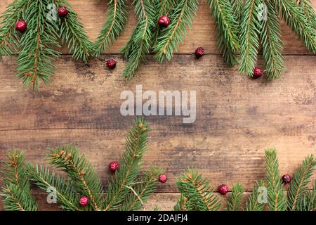 Arrière-plan de Noël avec branches de sapin et baies rouges. Cadre de vacances d'hiver avec brindilles à feuilles persistantes sur table en bois. Flat lay, espace de copie Banque D'Images