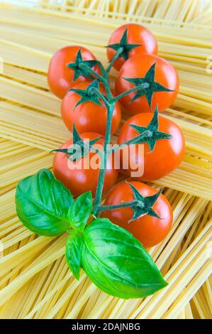 Tomate, basilic, tomates cerises, pâtes, spaghetti nourriture végétarienne, composition créative de tomates cerises. Basilic frais, tomates, concept de cuisine, vue du dessus Banque D'Images