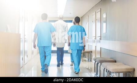 Vue arrière de l'équipe de médecins, d'infirmières et d'assistants marchant dans le couloir de l'hôpital. Personnel médical professionnel travailler, économiser Banque D'Images