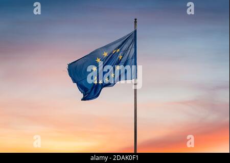 Drapeau de l'Union européenne en lambeaux/déchirés et arrière-plan de coucher de soleil Signifiant le coucher du soleil sur l'Union européenne - concept Banque D'Images