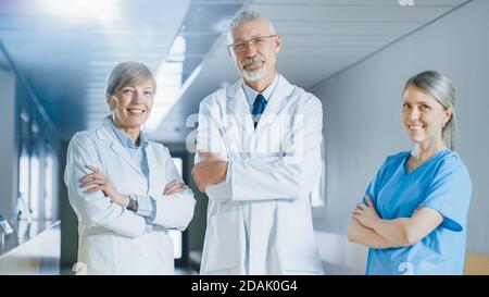 Portrait des médecins et des infirmières posant dans le bâtiment de l'hôpital, les bras croisés et souriant. Des gens brillants dans les professionnels de la santé qui sauvent des vies. Banque D'Images