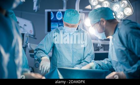 Équipe diversifiée de chirurgiens professionnels, d'assistants et d'infirmières effectuant une chirurgie invasive sur un patient dans la salle d'opération de l'hôpital. Utilisation par le chirurgien Banque D'Images