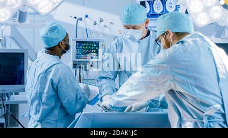 Équipe diversifiée de chirurgiens professionnels effectuant une chirurgie invasive sur un patient dans la salle d'opération de l'hôpital. L'infirmière remet les instruments au chirurgien Banque D'Images