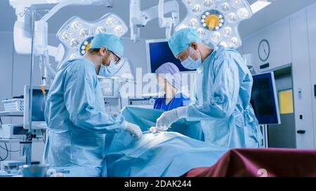 Dans la salle d'opération de l'hôpital équipe diversifiée de chirurgiens professionnels et d'infirmières Suture Winound après une chirurgie réussie. Banque D'Images