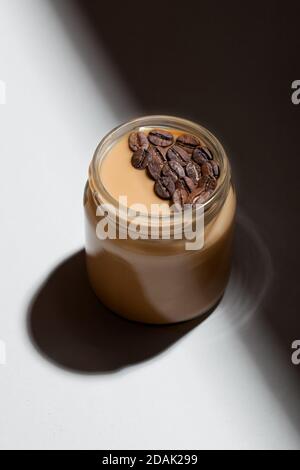 Dessert au yaourt aromatisé au café dans un pot en verre sur fond blanc. Mode de vie sain, superalimentation Banque D'Images