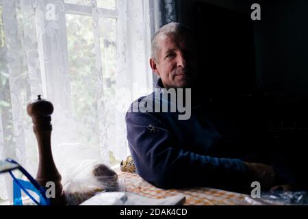 Un homme assis près de la fenêtre; l'ombre tombe sur la moitié de son corps et de son visage. Banque D'Images