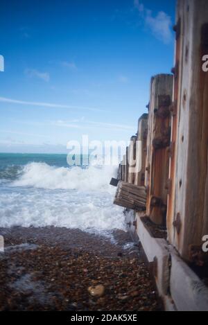 Brise-lames sur la plage de Hove, vagues écrasant, ciel bleu. Banque D'Images