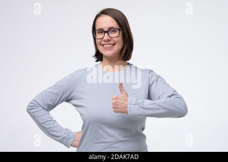 Jolie femme de race blanche montrant le pouce vers le haut, donnant des conseils. Banque D'Images