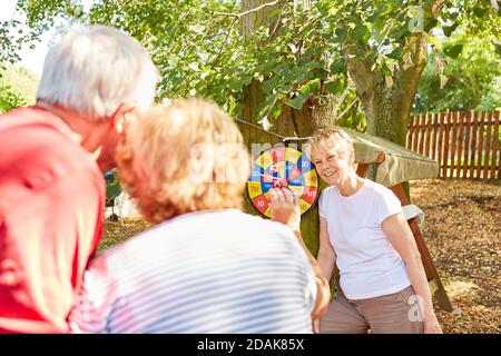 Les retraités âgés forment une équipe jouant aux fléchettes ensemble le jardin en été Banque D'Images