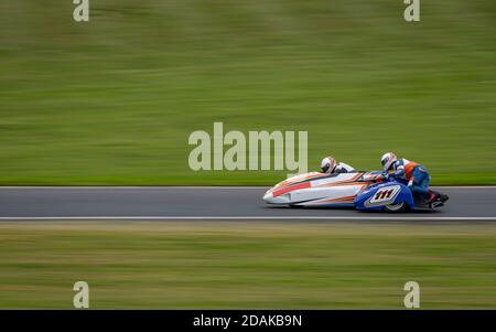 Un cliché panoramique d'un side-car de course en virage sur une piste. Banque D'Images