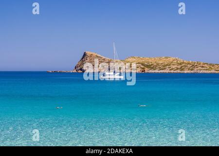 Nageurs et voiliers sur les eaux cristallines de la mer Egée en Crète, Grèce Banque D'Images