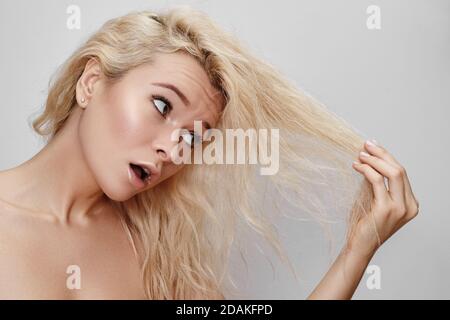 Mauvais jour de cheveux. Belle femme avec des cheveux foiré. Visage grimaquant malheureux. Coiffure blonde de blanchiment avec problèmes de cheveux fragiles Banque D'Images