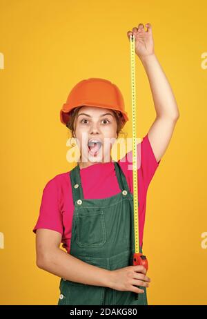 Mignon enfant en tant que travailleur de la construction. Enfant répare la maison. Enfance heureuse. Mètre-ruban en métal auto-rétractable. Petite fille utilisant un mètre ruban. Travailleur de construction avec mètre ruban. Banque D'Images