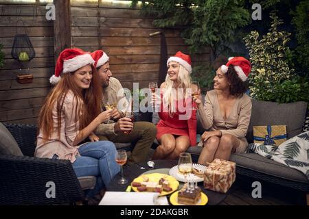 des amis qui parlent, sourient, rient, boivent, célèbrent la nouvelle année à l'extérieur, assis sur le canapé dans l'arrière-cour Banque D'Images