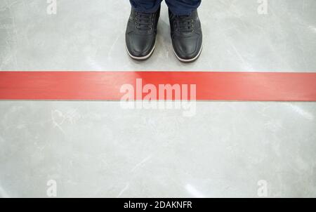 Une personne se tient à la ligne rouge sur le sol dans un centre commercial en gardant une distance sociale Banque D'Images