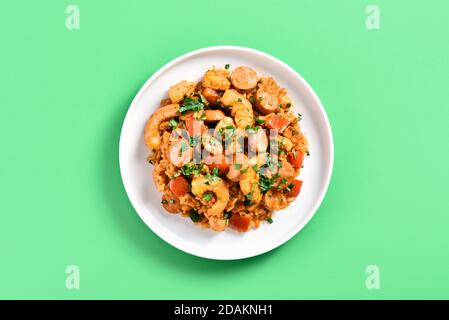 Vue rapprochée du jambalaya créole avec viande de poulet, riz, saucisses fumées et légumes sur un fond vert avec espace de copie. Vue de dessus, fl Banque D'Images