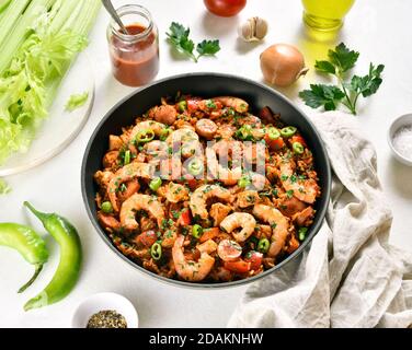 Jambalaya créole avec poulet, saucisses fumées et légumes dans une casserole sur fond de pierre blanche. Vue rapprochée Banque D'Images