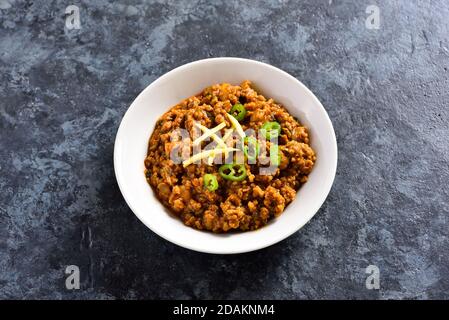 Vue rapprochée du curry de keema dans un bol sur fond bleu en pierre avec espace de texte libre. Plat de style indien et pakistanais. Banque D'Images