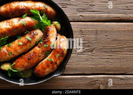 Vue rapprochée des saucisses grillées dans une poêle sur fond de bois. Vue de dessus, plan d'appartement Banque D'Images