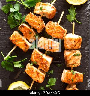 Vue rapprochée du kebab de saumon grillé. Faire griller des brochettes de saumon sur un panneau en pierre noire. Vue de dessus, plan d'appartement Banque D'Images