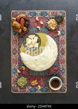 Ambiance de fête du Ramadan. Délicieux gâteau fait maison en forme de Crescent Moon, servi avec des dattes et une tasse de café. Vue de dessus. Banque D'Images