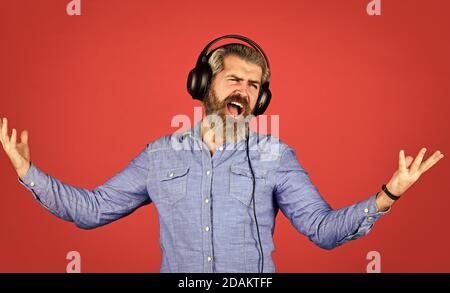 hipster homme barbu dans le casque. Écouter de la musique. Il est temps de se détendre. Les hippers brutaux portent des écouteurs. Chantent et dansent. Profiter de sa musique préférée. Homme écoutant de la musique avec son casque. Banque D'Images