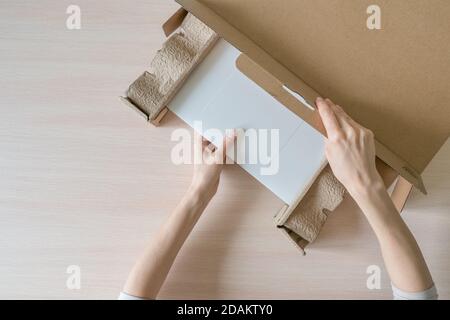 Déballage d'un nouvel ordinateur portable dans une boîte en carton. Les mains ouvrent la boîte. Déballage du colis reçu. Vue de dessus. Banque D'Images