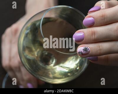 Main et verre de vin. Manucure créative avec coronavirus peint sur les ongles, mise au point douce, gros plan. Banque D'Images