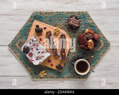 Bonbons faits maison à la marmelade avec fruits et noix de dattes, bonbons orientaux sur une surface en bois blanc. Banque D'Images