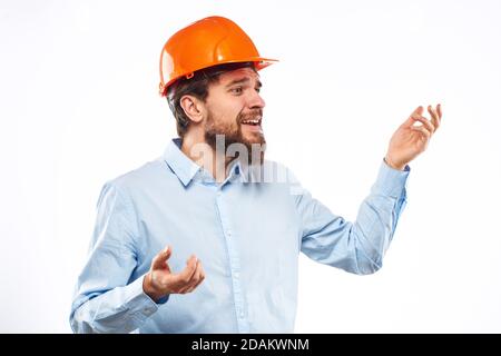 Un homme dans une industrie de construction de chemise de casque orange a travaillé arrière-plan clair Banque D'Images