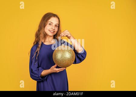 Préparez les décorations à l'avance. Une fille tient des décorations de boule dorée pour l'arbre de noël. Boutique d'accessoires décoratifs. Inspectez les décorations de Noël. Décor doré. Brillant métallique. Paillettes scintillantes. Banque D'Images