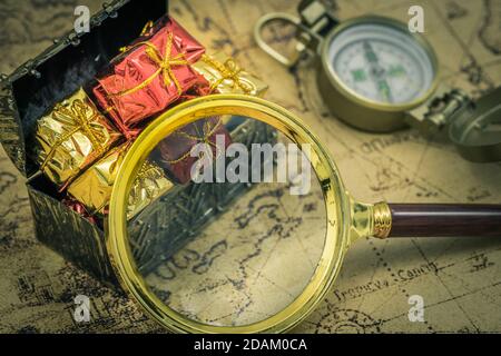 La chasse au Trésor. Une loupe et une boussole à côté d'une poitrine pleine de trésors. Ancienne carte, style vintage Banque D'Images