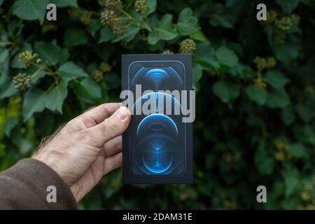 Paris, France - 11 novembre 2020: Main d'homme perspective personnelle à l'emballage du nouveau modèle de smartphone iPhone 12 Pro Max 5G par Apple Computers gros plan de l'appareil mobile Pacific Blue Banque D'Images