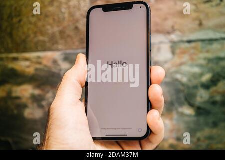 Paris, France - 11 novembre 2020: Hlo allemand bonjour mot dans la main de l'homme tenant le nouveau modèle de smartphone iPhone 12 Pro Max 5G par Apple Computers gros plan de l'appareil mobile Pacific Blue lors de la première configuration activation iOS Banque D'Images