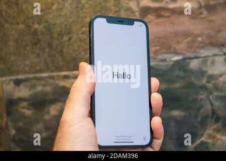 Paris, France - 11 novembre 2020: Hlo allemand bonjour mot dans la main de l'homme tenant le nouveau modèle de smartphone iPhone 12 Pro Max 5G par Apple Computers gros plan de l'appareil mobile Pacific Blue lors de la première configuration activation iOS Banque D'Images