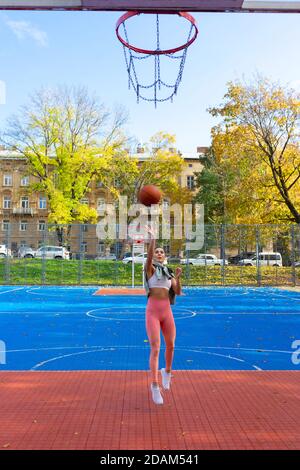 Une joueuse de basket-ball en saut jette le ballon dans le panier Banque D'Images