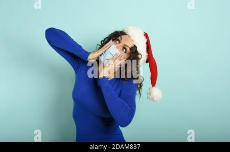 Femme avec masque de visage est demandé au sujet de quelque chose. Fond cyan Banque D'Images