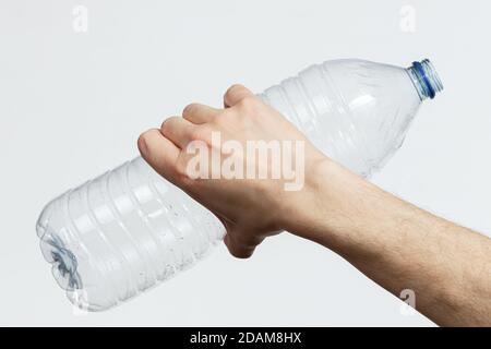 Main tenant une bouteille en plastique vide isolée sur fond blanc Banque D'Images