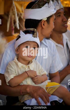 Garçon et père balinais en tenue traditionnelle assistant à un temple local pour le début du festival Galungan. Près d'Ubud, Bali, Indonésie Banque D'Images