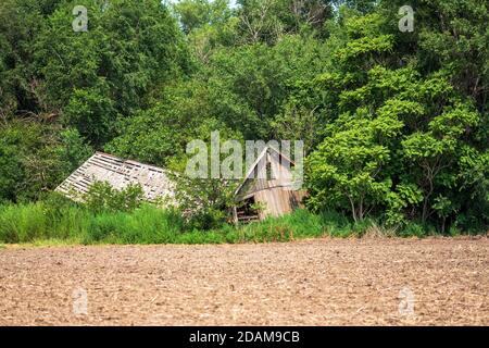 Abandon, délabrement et effondrement de la grange ou de la ferme dans la campagne à côté d'un champ labouré dans le Kansas, États-Unis. Banque D'Images