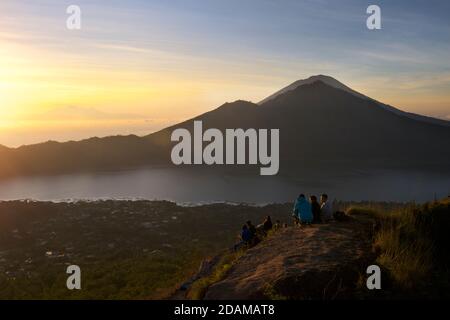 Randonneurs se rassemblant sur le bord de la caldeira du mont Batur pour le lever du soleil, Bali, Indonésie. Lac Batur ci-dessous. Banque D'Images