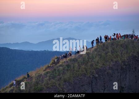 Randonneurs se rassemblant sur le bord de la caldeira du mont Batur pour le lever du soleil, Bali, Indonésie Banque D'Images