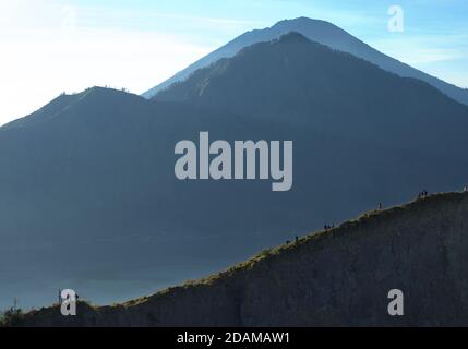 Randonneurs se rassemblant sur le bord de la caldeira du mont Batur pour le lever du soleil, Bali, Indonésie. Banque D'Images