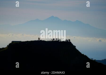 Mont Rinjani à Lombok vu d'une ascension du Mont Batur, Bali, Indonésie. Silhouettes de randonneurs contre la lumière froide du matin. Banque D'Images