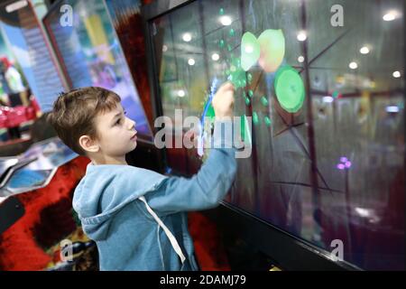 Enfant jouant à un jeu sur écran tactile dans un parc de divertissement Banque D'Images
