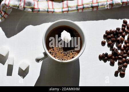 Cube de sucre tombant dans une tasse de café/UN cube de sucre déposé dans une tasse de café noir. Banque D'Images