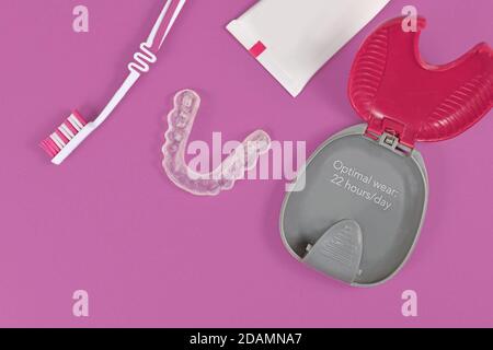 Dents transparentes personnalisées protège-dents aligneurs transparents pour mâchoire inférieure avec étui de rangement, brosse à dents et pâte sur fond rose Banque D'Images
