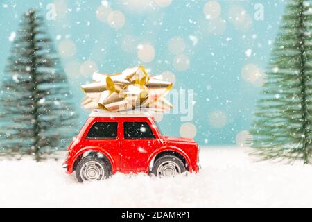 Carte de Noël ou du nouvel an avec voiture en peluche et sapin de noël miniature et lumières de bokeh de Noël sur fond. Banque D'Images