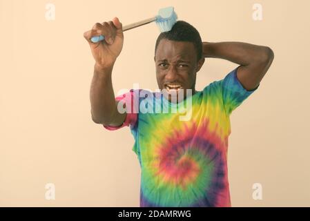 Photo en studio d'un jeune homme africain noir à l'aide d'une brosse de nettoyage pour laver ses cheveux sur fond blanc Banque D'Images