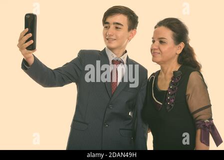 Studio de photo de jeune homme d'affaires persan heureux adolescent et mature Femme persane souriant tout en prenant des photos de selfie avec un téléphone portable ensemble Banque D'Images